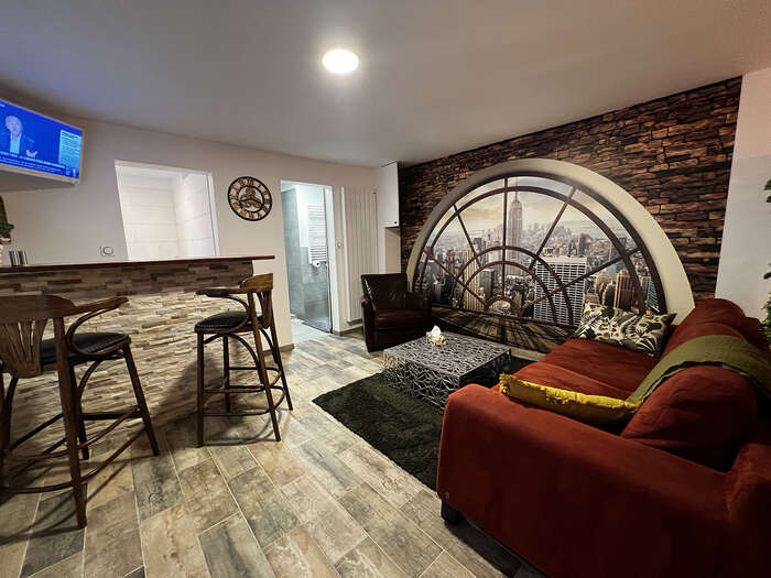 Salon avec bar et mur en pierres apparentes après rénovation — VBS Bâtiment